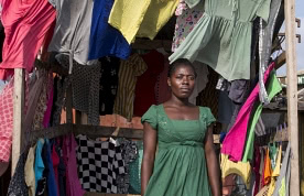 Ghanaian woman standing in clothing stall in wind